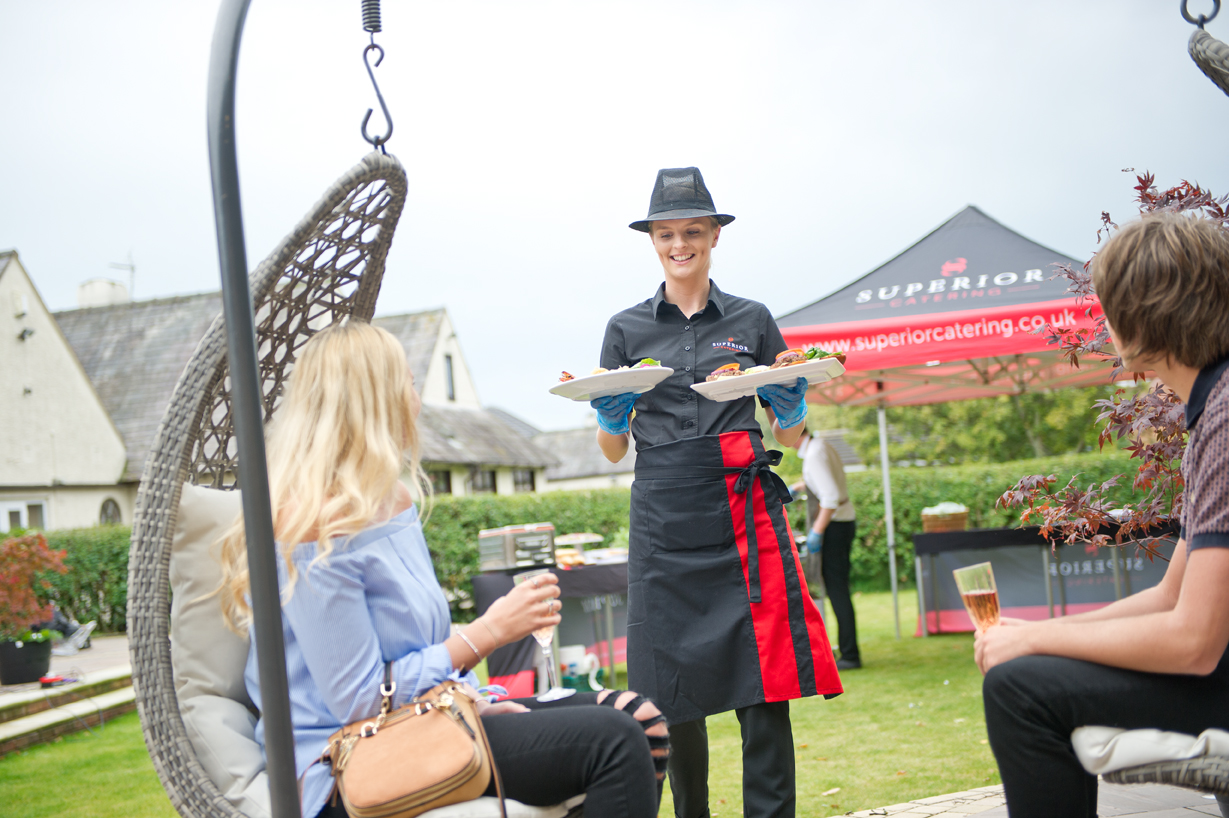 Hired catering assistant serving food outdoors