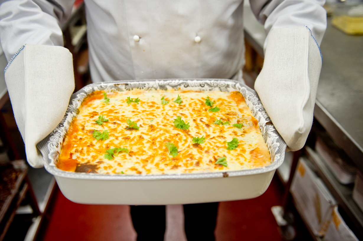 Lasagne in a dish being presented by chef at a corporate event