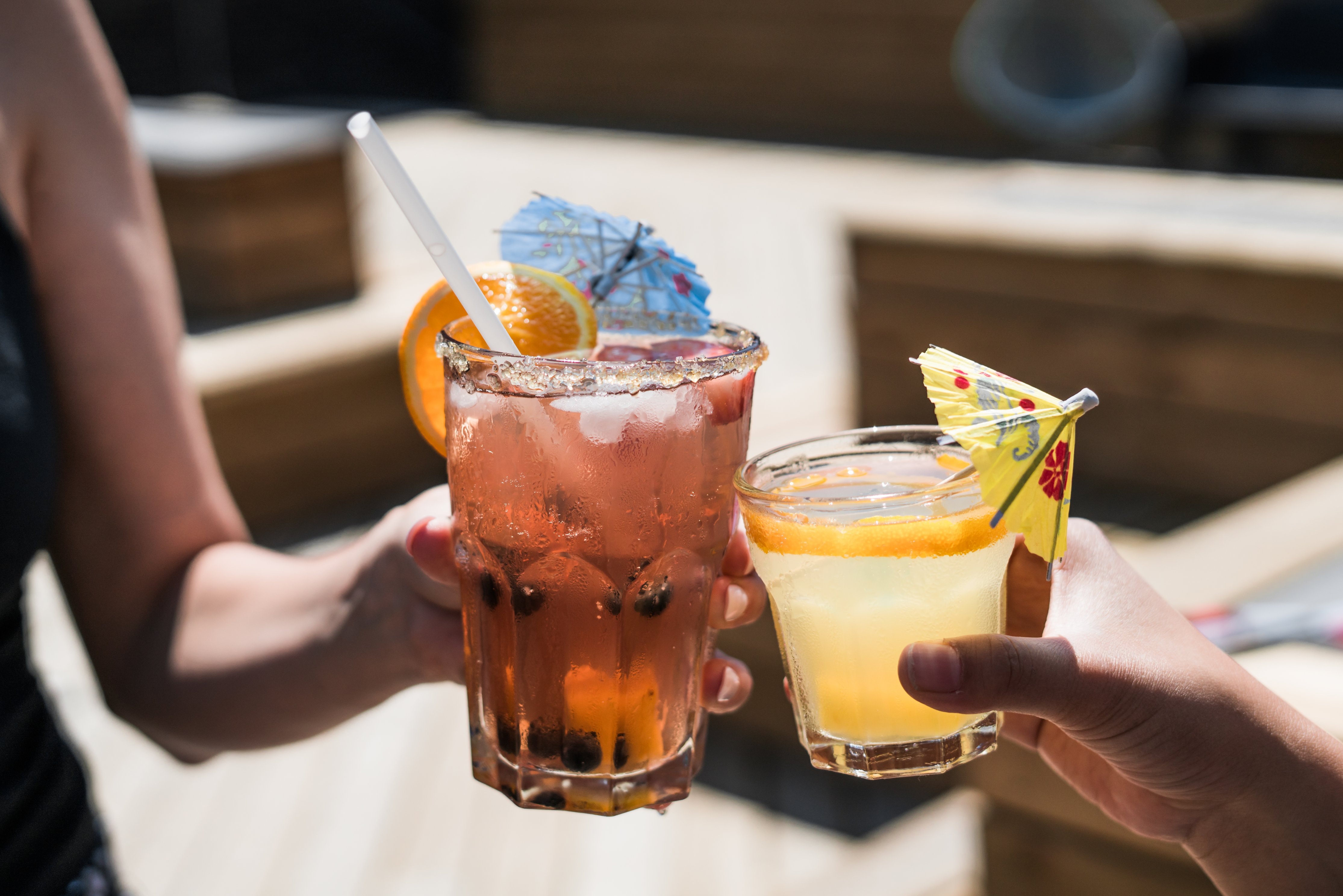 Two people drinking cocktails in an outdoors bar